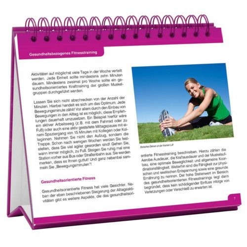 Offenes Buch mit Text über Gesundheits- und Fitnesstraining und einer Frau, die sich auf dem Gras streckt, mit einer rosa Spiralbindung.