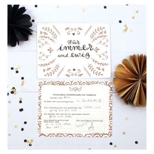 Hochzeitseinladung mit deutschem Text „Für immer und ewig“, floralem Rand, goldenen und schwarzen Papierfächern und Konfetti.