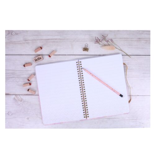 Aufgeschlagenes Notizbuch mit rosa Bleistift auf einem hellen Holztisch, umgeben von Stempeln und Trockenblumen.