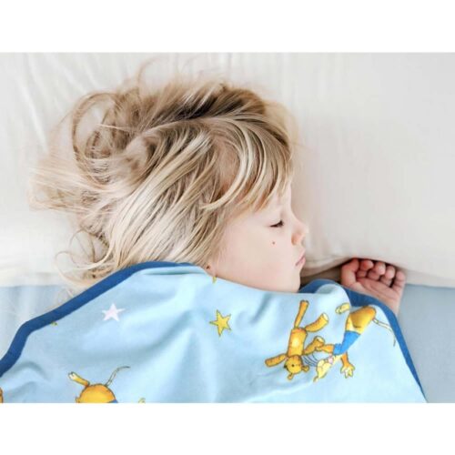 Kind mit blondem Haar schläft unter einer blauen Decke mit gelbem Bären- und Sternenmuster.