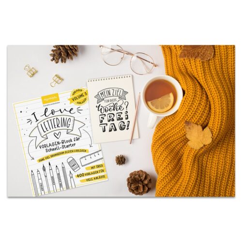 Gemütliche Herbstszene mit Buch, Notizblock, Brille, Tee, Tannenzapfen und gelbem Pullover auf weißem Untergrund.