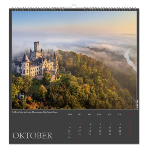 Kalenderseite mit Schloss Marienburg in Hannover, umgeben von Herbstbäumen und Morgennebel.