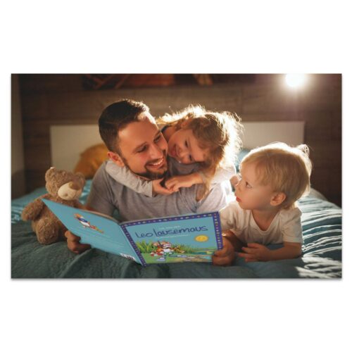 Vater und zwei Kinder lesen im Bett ein Buch