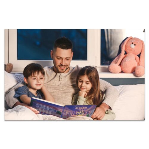 Ein Mann liest zwei Kindern auf einem Sofa eine Gutenachtgeschichte vor. In der Nähe sitzt ein Stoffhase.