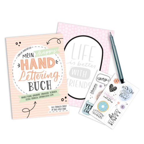 Ein Handlettering-Buch, Aufkleber und ein Bleistift auf weißem Hintergrund.