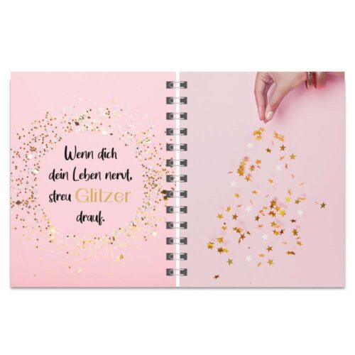 Aufgeschlagenes Notizbuch mit deutschem Text und einer Hand, die goldenes Sternkonfetti auf rosa Hintergrund streut.