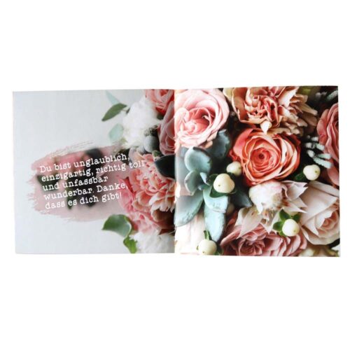 Offene Karte mit rosa Blumen und einer Nachricht auf Deutsch auf der linken Seite.
