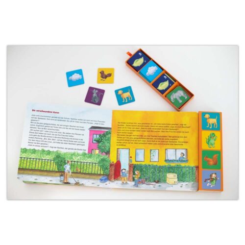 Kinderbuch mit illustrierten Seiten, Spielsteinen und verstreuten Tierkarten.
