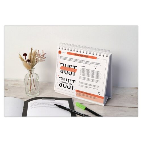 Schreibtisch mit Kalender, Notizbuch, Stift und Vase mit getrockneten Blumen.