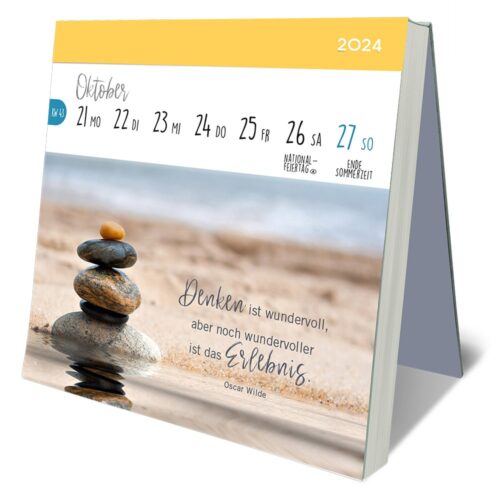 Tischkalender mit auf einem Strand gestapelten Steinen und einem Zitat auf Deutsch, der die Woche vom 21. bis 27. Oktober 2024 zeigt.