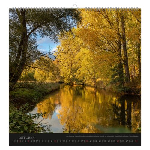 Eine ruhige Flussszene mit Bäumen in Herbstfarben, die sich unter einem klaren blauen Himmel im Wasser spiegeln.