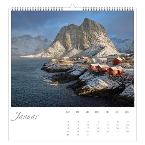 Verschneites Küstendorf mit roten Hütten, felsigen Klippen und einem grauen Meer unter einem bewölkten Himmel. Kalenderseite für Januar.