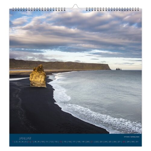 Küstenlandschaft mit schwarzem Sandstrand, felsigen Felsnadeln und bewölktem Himmel in einem Kalenderfoto für Januar.