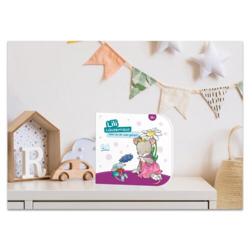 Kinderbuch auf einer Kommode mit dekorativem Haus, Spielzeugauto und hängenden Sternen und Flaggen im Hintergrund.
